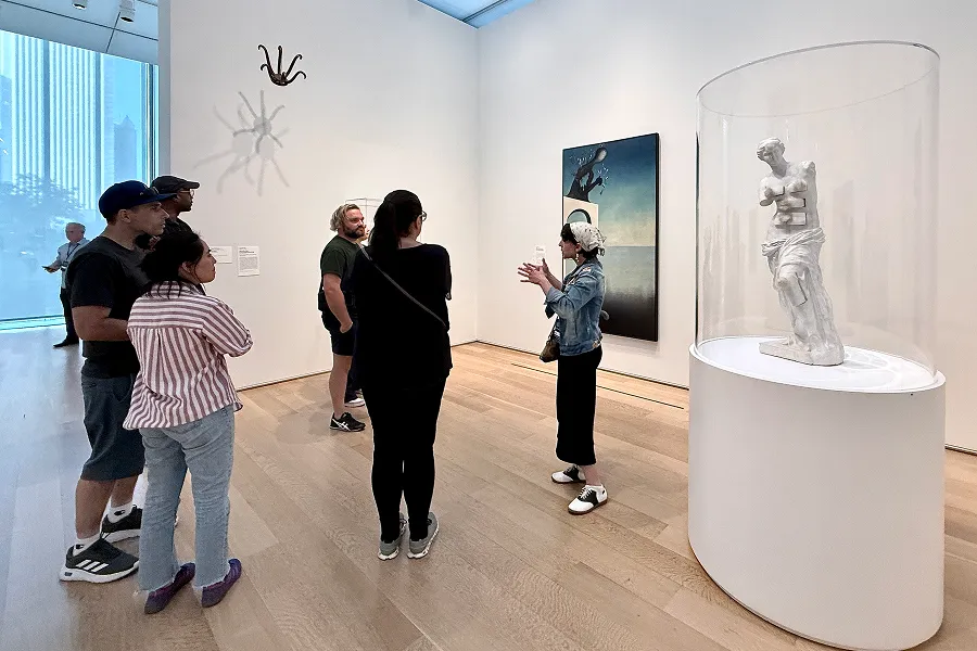 A group of people being led through the Art Institute by a Chicago Museum Tours guide, observing a sculpture together